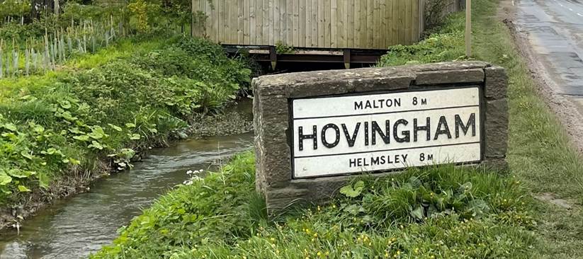A road with a sign and a house
Description automatically generated